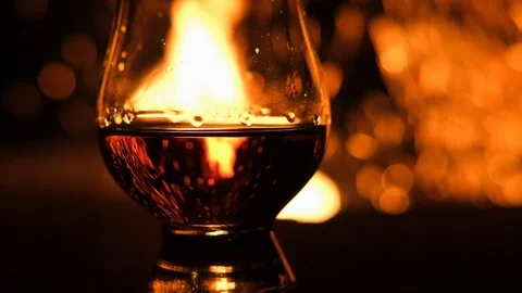 Close Up of Fire Flames Reflecting on a Glass of Scotch Whiskey Stock Footage 123381217