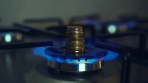 Close up fire gas burning on stove burner with stack of coins Stock Footage 202532280