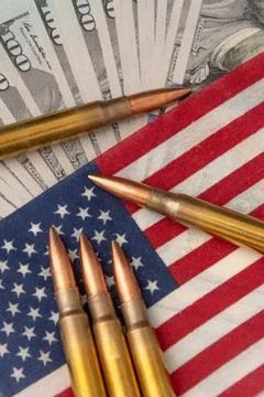 Close-up of firearm ammunition lying on an American flag with blurred dolla.. Photos