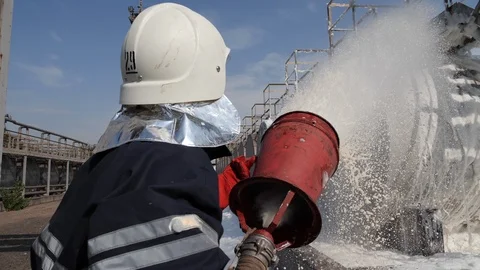 Close-up. Firefighter puts out a fire on a tank with oil products Stock Footage 115795161