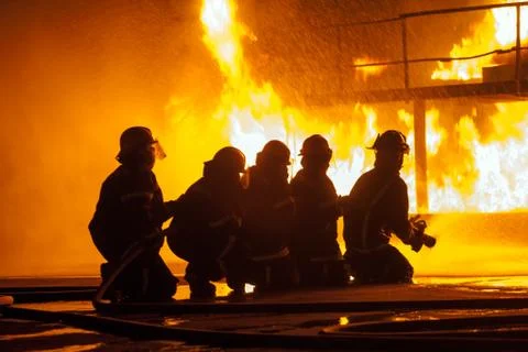 Close up of firefighters spraying burning structure during firefighting exe.. Stock Photos
