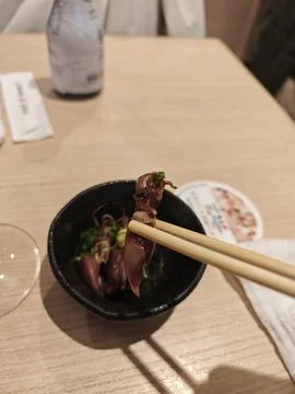 Close-up of Firefly Squid Held by Chopsticks in Japanese Restaurant Фото