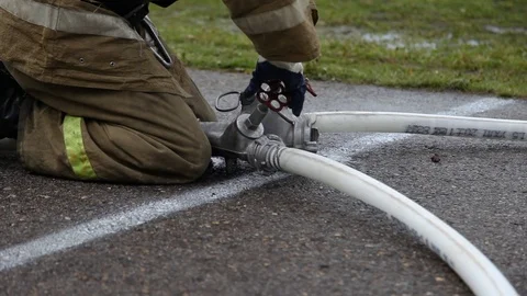 Close up of a fireman with hose splitter and fire hoses, unscrews the valves Stock Footage 122524341