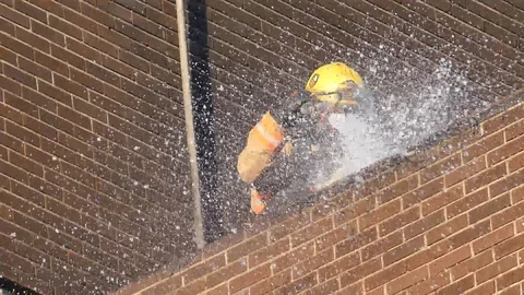 Close up of fireman watering building with water jet Stock Footage 90360106