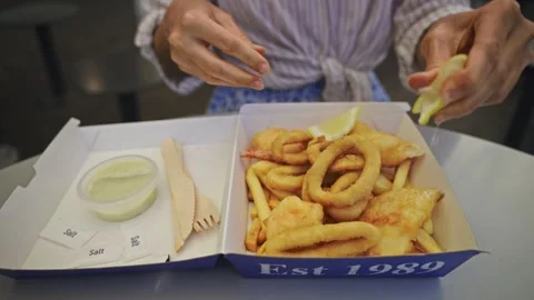 Close-up of fish and chips in a cardboard takeaway box, with female hands Stock Footage 308320315