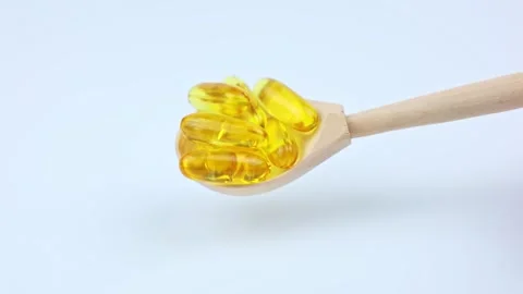A close-up of fish oil capsules on a white background lies in a wooden spoon, it Stock Footage 307168128