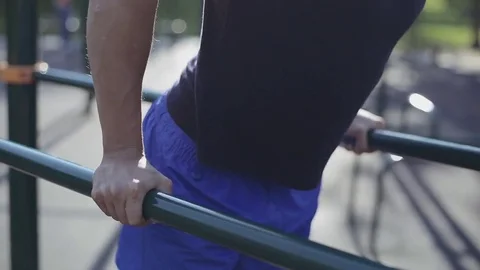 Close up of fit man doing triceps dips on parallel bars at park Stock Footage 83676672