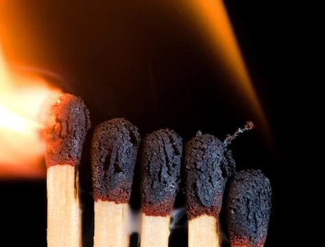 Close-up of five burning matches on black background. Stock Photos