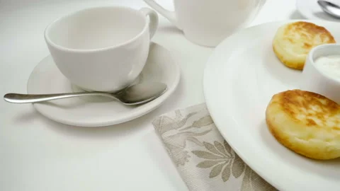 Close-up of five cheesecakes and sour cream on a white plate. Slow motion. HD Stock Footage 107434735