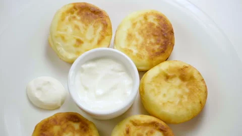 Close-up of five cheesecakes and sour cream on a white plate. Slow motion. HD 库存影片 107434951