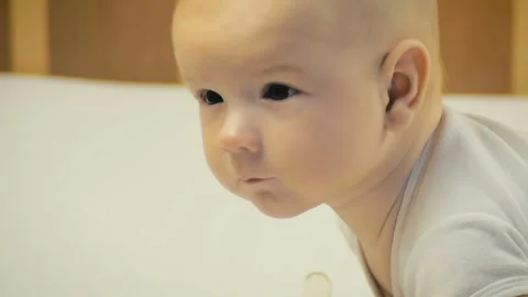 Close-up of a five-month baby lying on his tummy in bed in slow motion. Video stock 97918791
