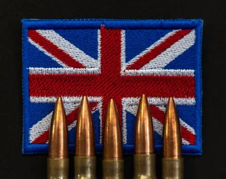 Close up of five rifle bullets standing in front of the Union Jack flag patch Stock Photos
