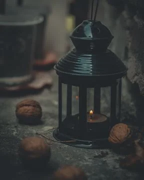 Close-up of a flashlight with a burning candle surrounded by walnuts. Dark photo Stock Photos