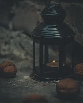 Close-up of a flashlight with a burning candle surrounded by walnuts. Dark photo Stock Photos