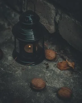 Close-up of a flashlight with a burning candle surrounded by walnuts. Dark photo Stock Photos