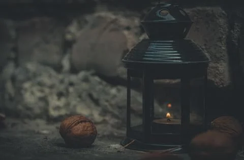 Close-up of a flashlight with a burning candle surrounded by walnuts. Dark photo Stock Photos