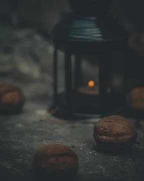 Close-up of a flashlight with a burning candle surrounded by walnuts. Selective Stock Photos