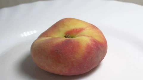 Close-up of a flat donut peach rotating on a white turntable against a ligh.. Stock Footage 337774809