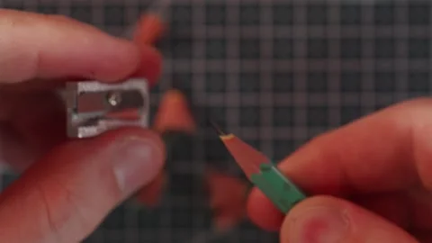 Close up flat lay of hands sharpening wooden graphite pencil Stock Footage 340139133