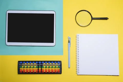 Close up flat lay with laptop, abacus, noteook and pen on yellow background. Stock Photos