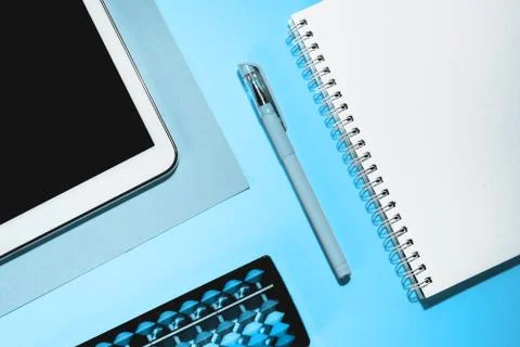 Close up flat lay with laptop, abacus, noteook and pen on blue background. Stock Photos