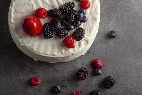 Close up flat lay low light image of a round cake with creamy white icing Stock Photos