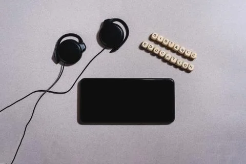 Close up flat lay of mobile phone with headphones and little wooden bricks. Stock Photos