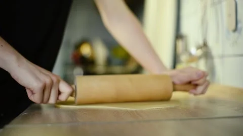 Close up of flattening raw dough sheet with a wooden rolling pin Stock Footage 342704121
