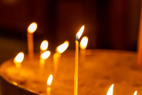 Close-up of flickering candle flames casting a warm glow in a dimly lit space Stock Photos