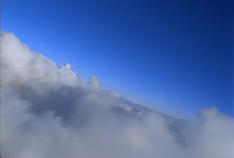 A close flight over the tops of white puffy clouds begins with the horizon on a Stock Footage 86832397