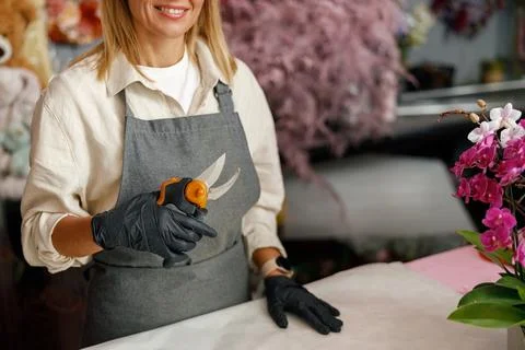 Close up of florist composing bouquet while standing near workplace with tools Foto stock
