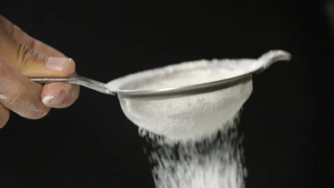 Close-up of flour through a sieve fray. Sifting flour baking. Black background. Stock Footage 127796922