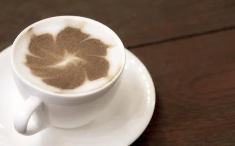 Close up flower pattern of cappuccino latte art in white ceramic cup on woo.. Stock Photos