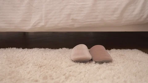 A close-up of fluffy white carpet and light brown slippers on it. Stock Footage 100472659