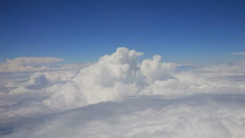 Close-up of fluffy white clouds against a blue sky taken from an airplane in  Stock Footage 293498431