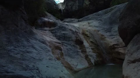 Close Up Flying Through Rock Formation Over Gentle Waterfall Stockbeeldmateriaal 159828226