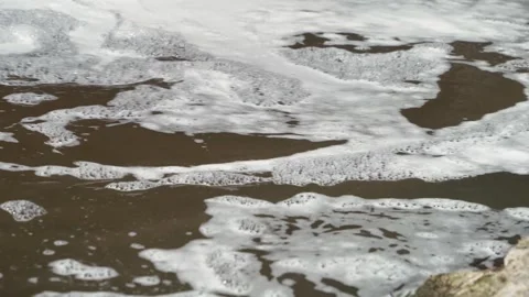 Close up of foam on water next to a rapids in nature Stock Footage 338222946