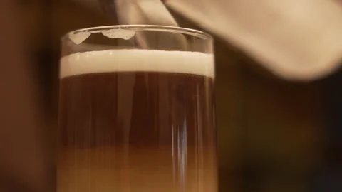 Close-up of foamed milk being poured into a layered coffee drink Stock Footage 336620796