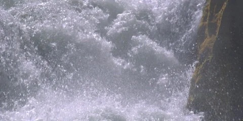 Close-up foaming water falling past a mossy boulder Stock Footage 59102997