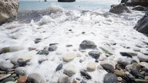 Close up of foamy waves rolling over smooth, multicolored pebbles on the beach Vídeos de archivo 331701984
