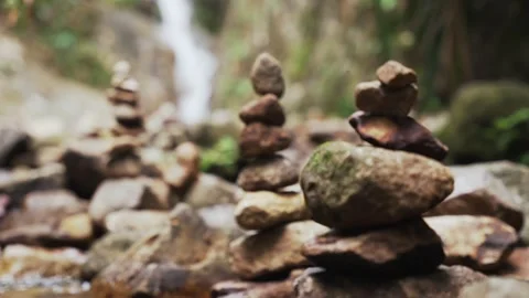 Close-up focus change effect of a carefully balanced zen stone towers near a Stock Footage 309276977