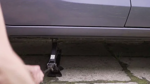 Close focus on dirty mechanics hands screwing big wheel bolts while changing Video stock 78607517