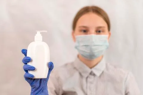Close-up focus on a gloved hand with bottle of antiseptic liquid soap, teenager 스톡 사진