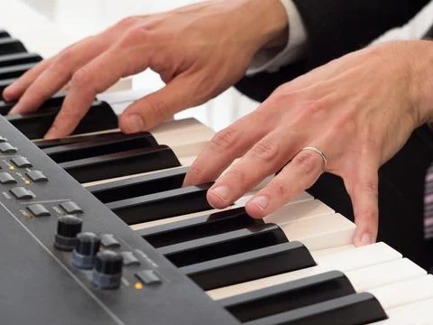 Close up focus on one of two hands playing a keyboard . Stock Photos