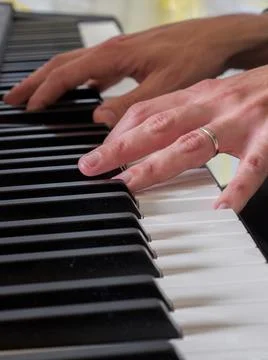Close up focus on one of two hands playing a keyboard . Stock Photos