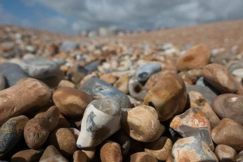 Close focus on pebbles on a beach with blurred shore and buildings in back Stock Photos