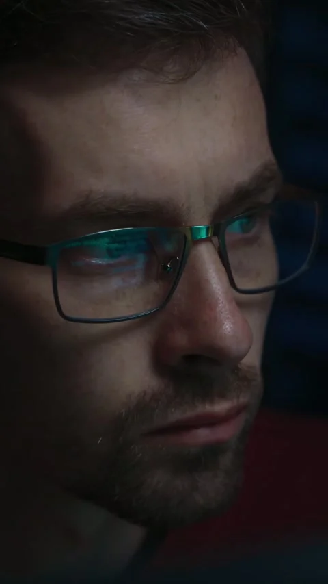 Close-up of a focused coder in glasses working in a dark workspace Video stock 345446297