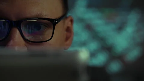 Close-up of a focused individual working on a laptop at night in a dimly lit Stock Footage 323730556