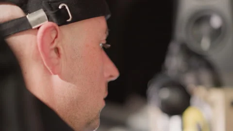 Close-Up of Focused Man in Black Cap with Blurred Speaker in Background Stock Footage 284367911