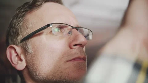 Close-up of a focused man with glasses, a computer screen reflecting in his Stock Footage 314250222